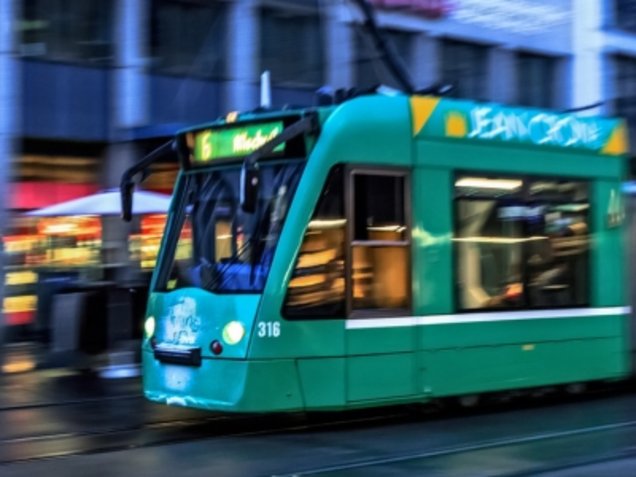 Grüne Straßenbahn in Fahrt bei Dämmerung. Verkehrsmittelwerbung auf Schienenfahrzeugen erzielt besonders in stark frequentierten Innenstädten eine große Reichweite.
