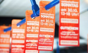 Innenansicht eines Linienbusses mit auffälligen Werbeanhängern an den Haltegriffen. Diese Form der Verkehrsmittelwerbung erreicht Fahrgäste direkt während der Fahrt.